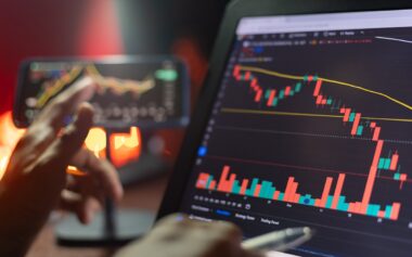 An Investor Analysis The Stock Market Exchange From The Candlestick Graph. Trader At Home Office Trading On Computer And Using Mobile Phone. Financial And Broker Agent Investment Concept.
